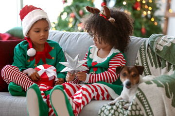 Little African-American children with Christmas gift at home