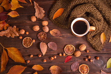 Autumn, fall leaves, hot cup of coffee and warm scarf on wooden table background, top view, copy space. Seasonal, morning coffee, sunday relaxing and still life concept.