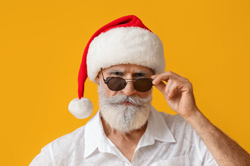 Cool senior man in Santa hat on color background