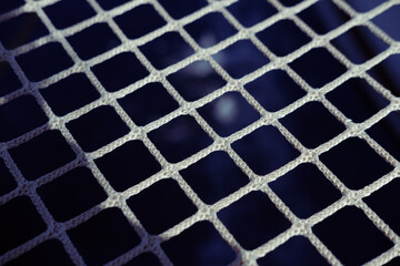 Catamaran net of artificial fibres on water background, dark blue, white ropes, close up