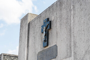 Stone cross with Jesus on concrete grave in a cemetery
