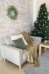 Interior of living room with Christmas tree, mistletoe wreath and sofa