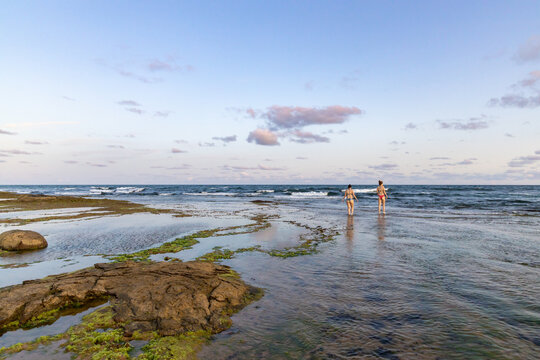 Praia paradis&iacute;aca com duas mulheres distantes ao fundo. Conceito de viagem e f&eacute;rias. 