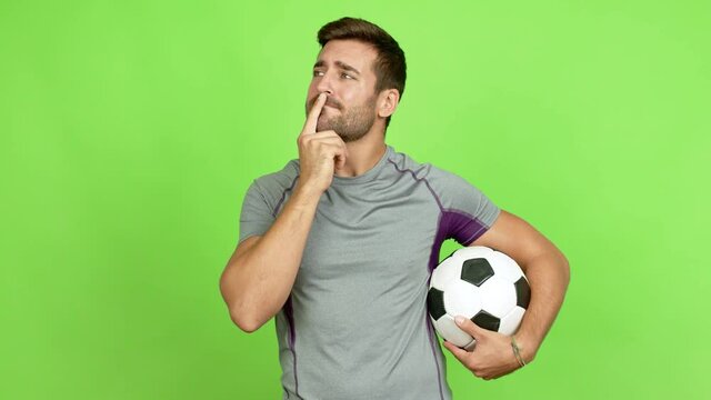 Handsome man thinking and holding a soccer ball over isolated background