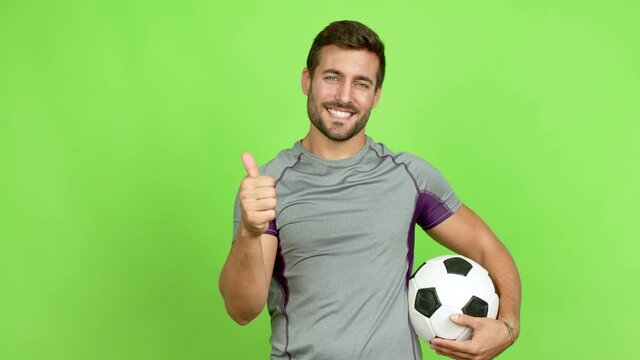 Handsome man playing futbol and with thumb up over isolated background