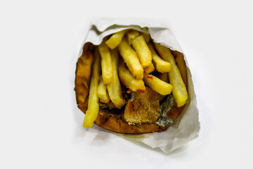 Greek gyros wrapped in pita bread isolated on white background. Fast food concept. Gyros with meat, fries and tzatziki salad