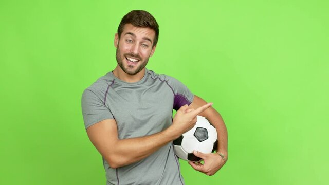 Handsome man playing futbol and pointing side over isolated background
