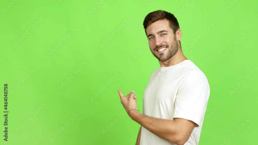 Wall mural Handsome man pointing back and presenting a product over isolated background