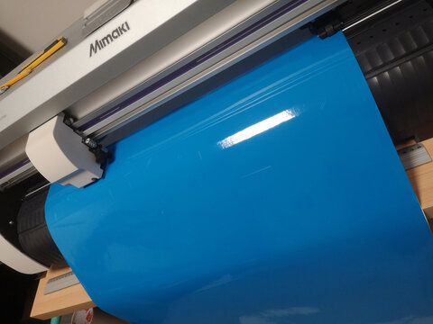 Brno, Czech Republic - 26 April 2021: Production of stickers on a cutting plotter intended for a vehicle from blue foil
