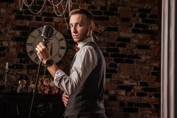 man in suit posing with condenser microphone. Emotional young man with a microphone in his hands