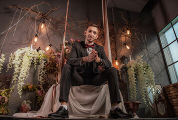 emotional man in suit posing on vintage swing