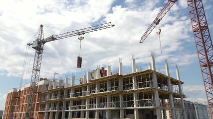 Tower cranes and workers at high concrete residential building under construction. Real estate development concept. Kyiv, Ukraine - July 21, 2021. - Powered by Adobe