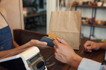 Close-up of unrecognizable customer paying with wireless card and putting it to terminal in shop of handmade goods