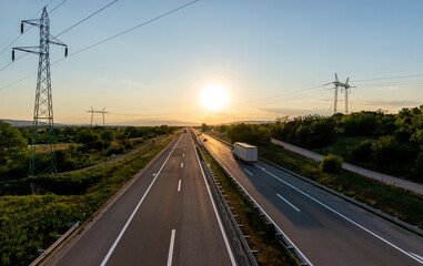 White truck in the countryside passing through green-blue nature on the highway.