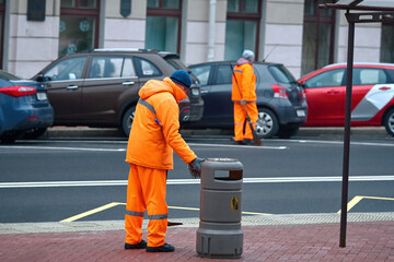 Street sweaper team clean up road and pedestrian zone in the city. Municipal workers sweep city...