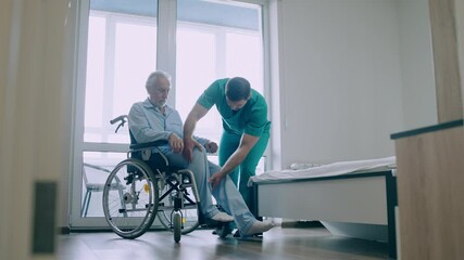 Hospital worker taking care of elderly patient with physical disability, support