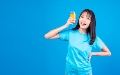 Healthy fruit vitamin beverage concept. Enjoy leisure young woman wear casual holding glass with fresh organic orange juicy in own hands while standing feeling relax over isolate blue background.