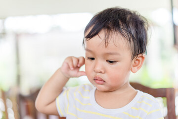 Little asian toddler baby boy has earache when insects inside outdoor baby infant boy hands touching in ear and pain.deaf kid.Flu and sick.Clean up earwax.Accident in kid with ear.Condition and clean.