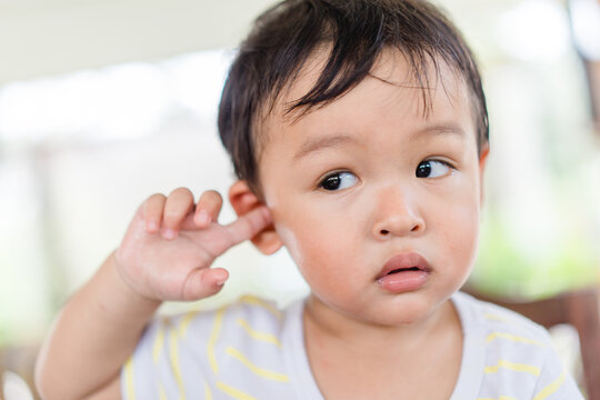 Little asian toddler baby boy has earache when insects inside outdoor baby infant boy hands touching in ear and pain.deaf kid.Flu and sick.Clean up earwax.Accident in kid with ear.Condition and clean.