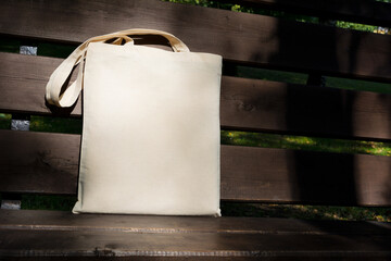 Canvas tote bag in the sunlight on the bench mockup