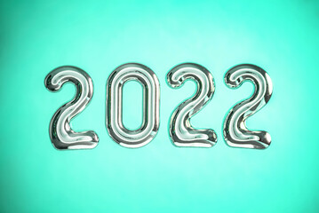 Volumetric metallic silver numbers 2022 on a green background. Greeting on the New Year. Top view and copy space