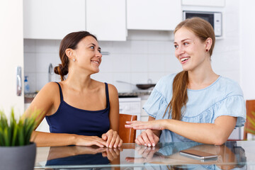 Fototapeta premium Two friendly girls having emotional conversation in kitchen interior