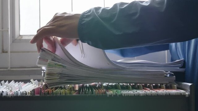 Close-up hand of businessman searching for financial and accounting file paperwork in an office file cabinet