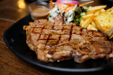 Beef steak on a black plate on a wooden table, close-up shot