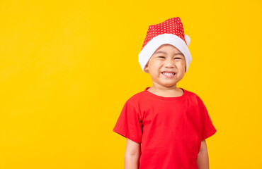 Kid dressed in red Santa Claus hat, Portrait of Asian little cute boy smile and excited the concept of holiday Christmas Xmas day or Happy new year, studio shot isolated on yellow background