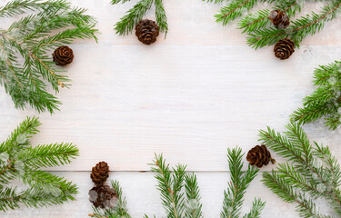 Fototapeta na wymiar Spruce branches and cones on a white wooden background. Christmas layout with space for your text. 