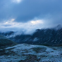 Snowy field with mountains and low hanging clouds