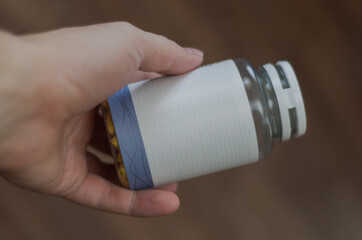 closed jar of pills in hand