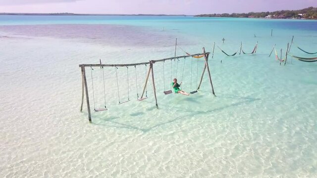 Girl swinging in Bacalar Lagoon in Mexico.