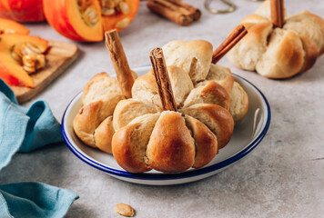 Pumpkin buns bread with cinnamon on enamel plate. Autumn, Halloween food concept.