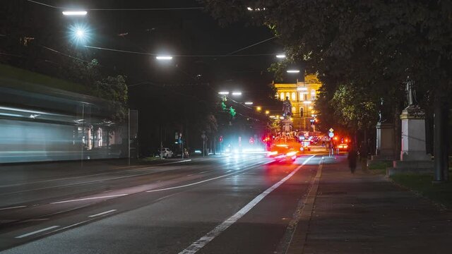 Night time lapse of road traffic in Munich. Cars and streetcars drive on street and drag light trail behind them. Busy downtown area in Germany