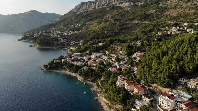 Brela city coast on hillside, aerial forward pan down.