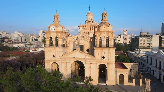 Cinematic aerial dolly in shot toward the statue of Christ in between two clock towers, historic monument Cathedral of Cordoba, Argentina.