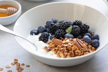 Granola with yogurt, blueberries and blackberries on a concrete background