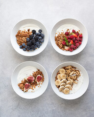 Breakfast, granola with yogurt, berries, fruits and nuts on a light background, view from above