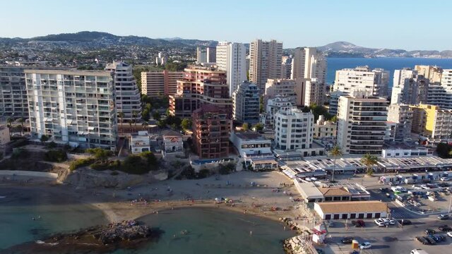 Drone clip over a beautiful tropical beach in Calpe, Spain with hotels and resosrts in the background