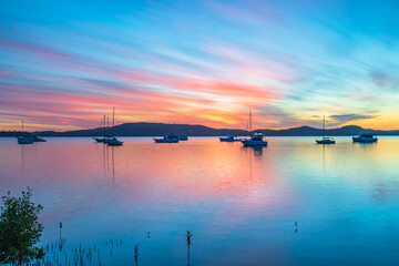 Sunrise waterscape with boats, reflections and high cloud