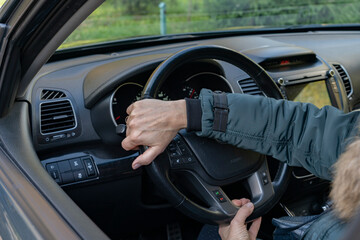 Women's hands turn the steering wheel in the car.