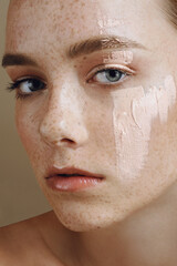 Young beautiful girl with perfect health freckled skin and  mask cream on face