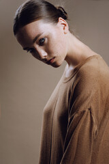 Attractive fashion girl with freckles face and nude makeup in cozy knitted autumn dress posing in studio