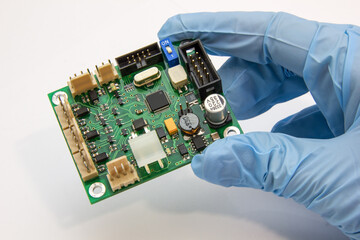 Hand in a blue glove holds pcb chip assembly on pcb backround on the production of printed circuit...