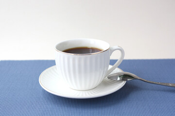 White porcelain cup and saucer with a gold rim on a white and blue background. A pair of tea and a...