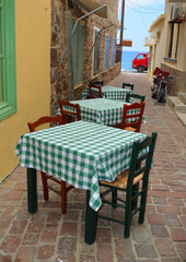 Three Cafe tables in alleyway leading to the sea 