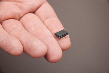 Hand holds chip compenent. Embedding the chip under human skin, microcontroller implanting NFC...