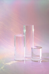 Abstract surreal scene - empty stage with three clear glass cylinder podiums on pastel pink...