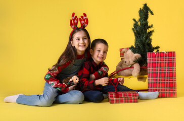 Obraz na płótnie Canvas Kids with gifts on a yellow background for the Christmas holidays